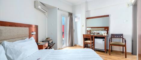 Una habitación de hotel con cama, escritorio, silla y una pequeña cocina.