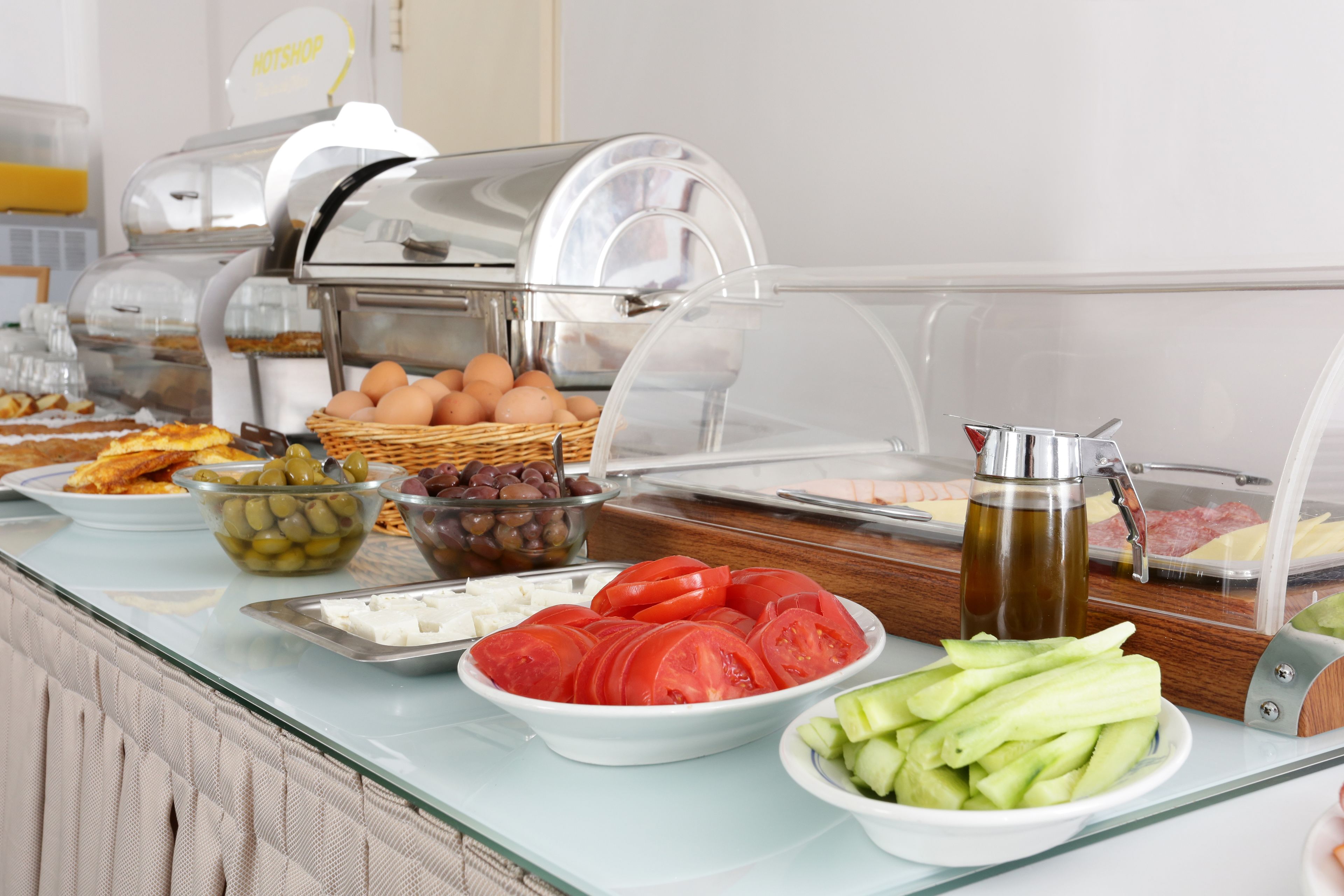 Un bufé con diversas opciones de comida, como huevos, tomates, pepinos y aceitunas.