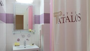 Un baño con lavabo blanco, espejo y cortina de ducha rosa.