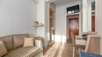 Una habitación moderna con un sofá color beige, un escritorio de madera con una computadora, una silla y un armario.