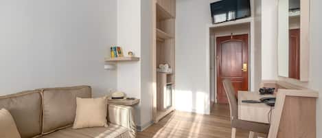 Ein modernes Zimmer mit einem beigen Sofa, einem Holztisch mit Computer, einem Stuhl und einem Kleiderschrank.