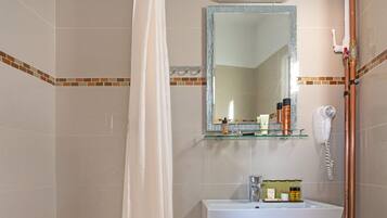 A bathroom with a shower, a sink, a mirror, and toiletries on the wall.
