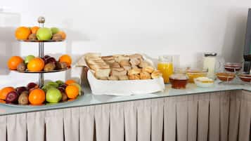A breakfast buffet with fruits, pastries, and beverages.