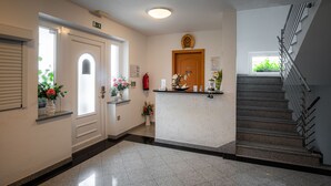 A reception area with a reception desk, a clock, and a staircase. - Penzion Kovac (Radovljica)