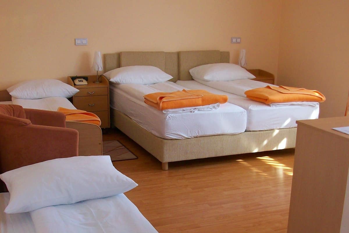 A hotel room with two single beds, a sofa, a nightstand, and a desk.