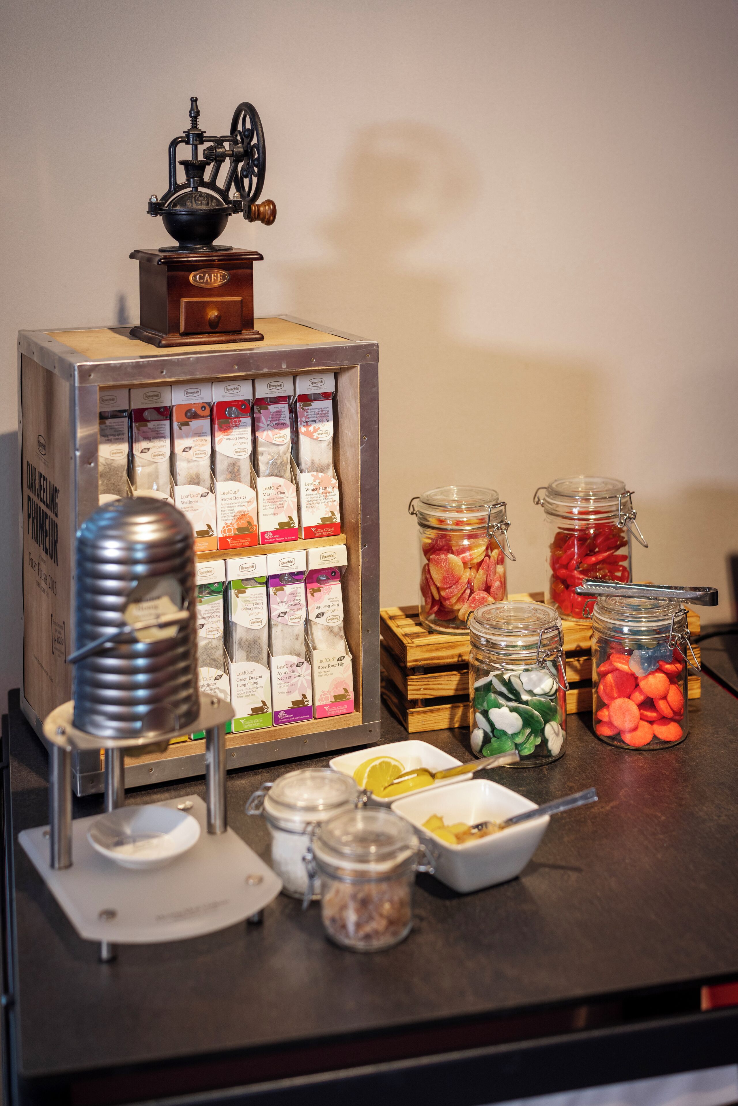 A buffet setup with a coffee machine, jars of pickled vegetables, and a variety of packaged foods.