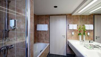 Une salle de bain moderne dotée d’une douche à parois de verre, d’une baignoire et d’un grand meuble-lavabo avec un miroir.