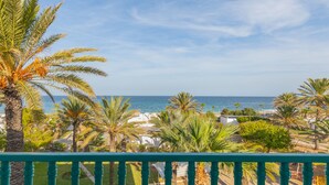 A balcony with a view of the sea, palm trees, and a white building in the background. - El Mouradi Port El Kantaoui (Port El Kantaoui)