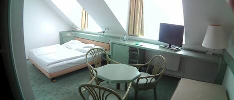 Una habitación de hotel con una cama, un escritorio, una silla, un televisor y una ventana con cortinas.