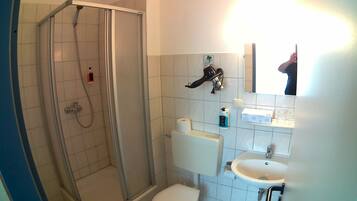 Une salle de bain avec une douche à parois de verre, des toilettes, un lavabo et un miroir.