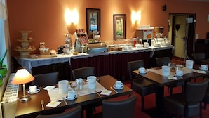 Buffet d'esmorzars amb diferents aliments i begudes, disposats sobre una taula amb mantell de puntes.