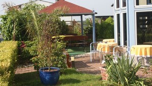 Una zona de pati amb seients exteriors, una estructura coberta i plantes en testos.