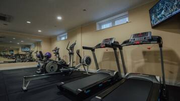Ein Fitnessstudio mit Laufbändern, Crosstrainern und stationären Fahrrädern.