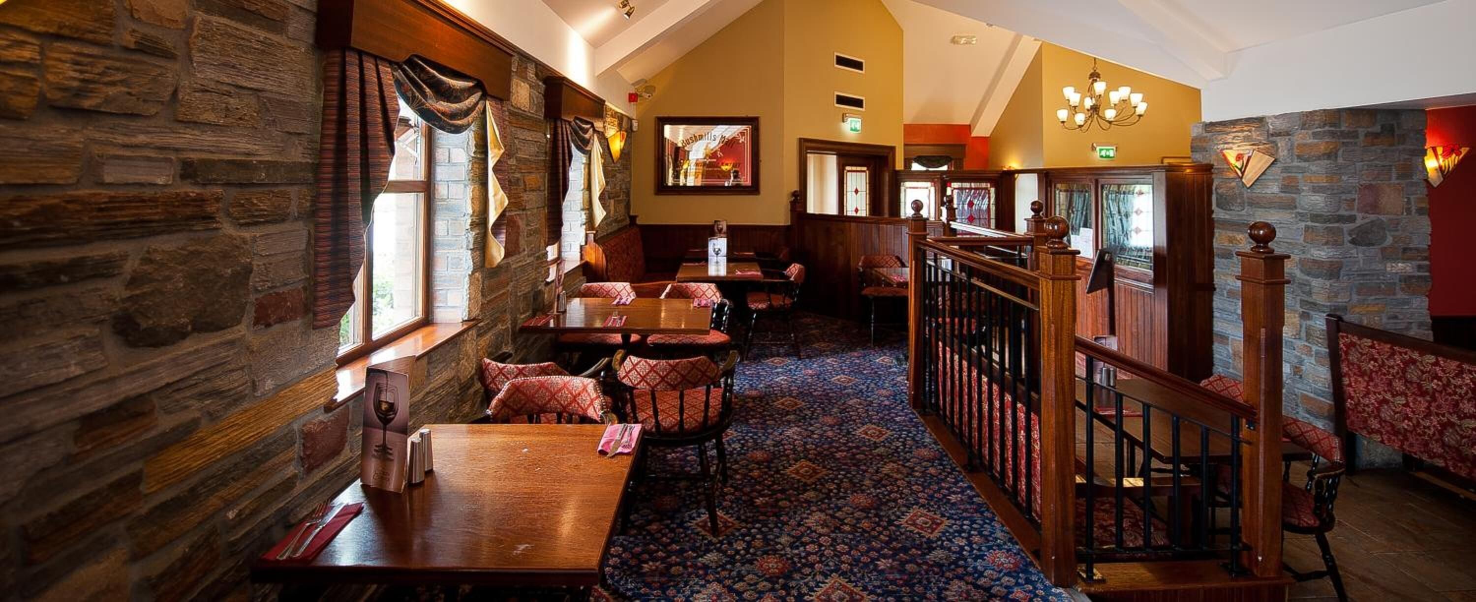 A restaurant with stone walls, wooden tables, and patterned carpet.