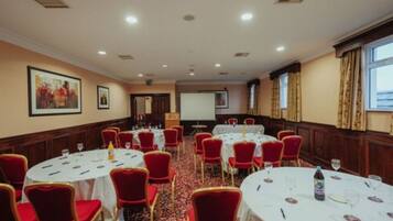 A conference room with round tables, red chairs, and a projector screen.