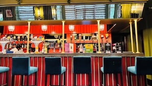 A bar area with a counter, bar stools, and shelves stocked with bottles. - Uno Thames Hotel (Maidenhead)