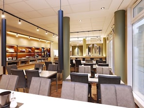 A modern restaurant with high tables and chairs, a bar area, and a large window. - B&B HOTEL Berlin-Mitte (Berlin)