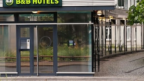 Un hotel B&B con fachada moderna, amplios ventanales y el número 25 visible.
