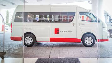 A white van with red accents parked at a hotel entrance.