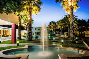 A pool area with a fountain, palm trees, and outdoor seating.