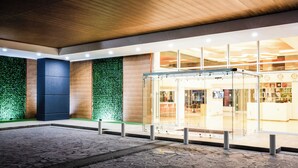 A modern building entrance with a glass door, a wooden ceiling, and a green wall.