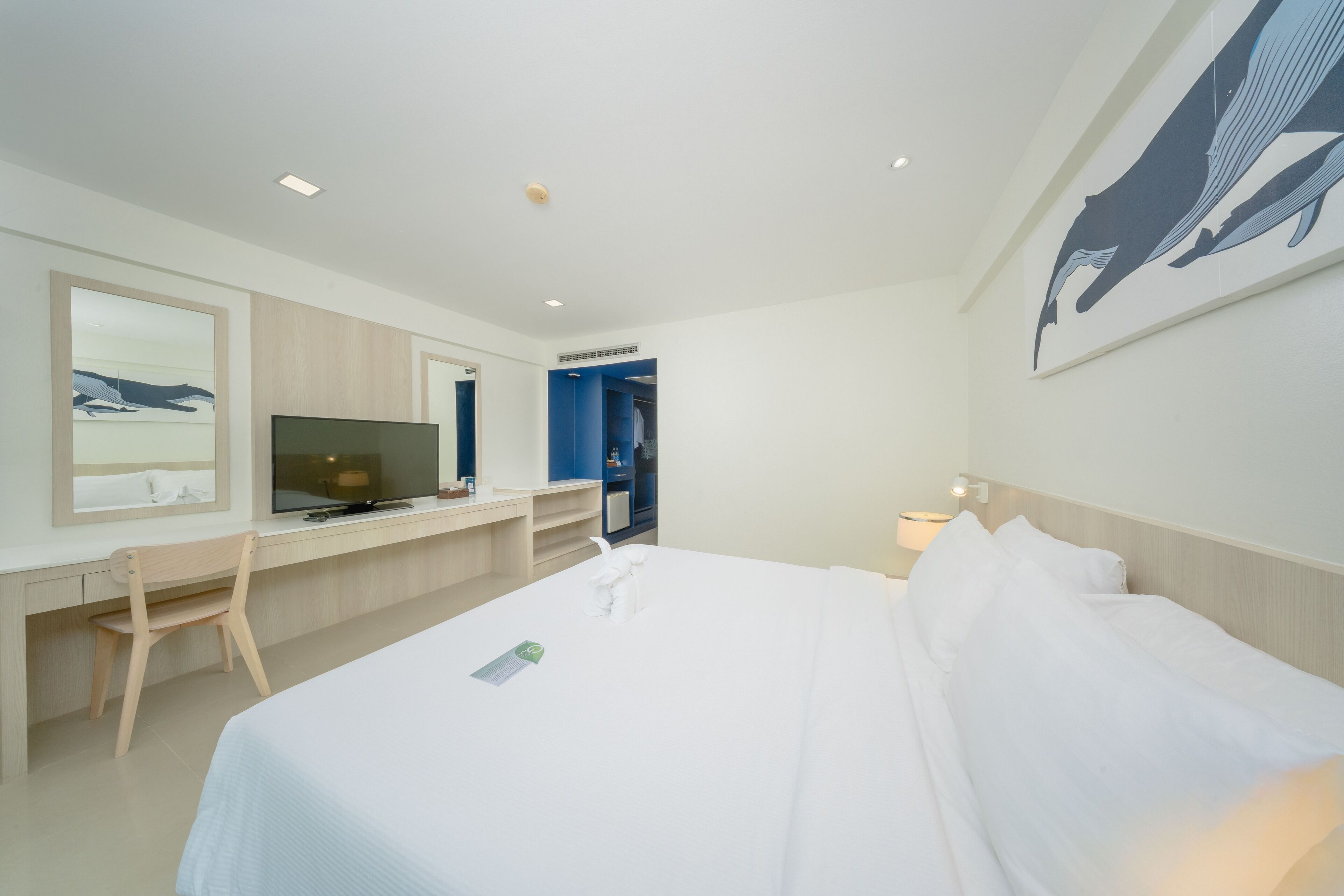 Habitación de hotel con cama, escritorio con computadora, televisor y ventana grande.