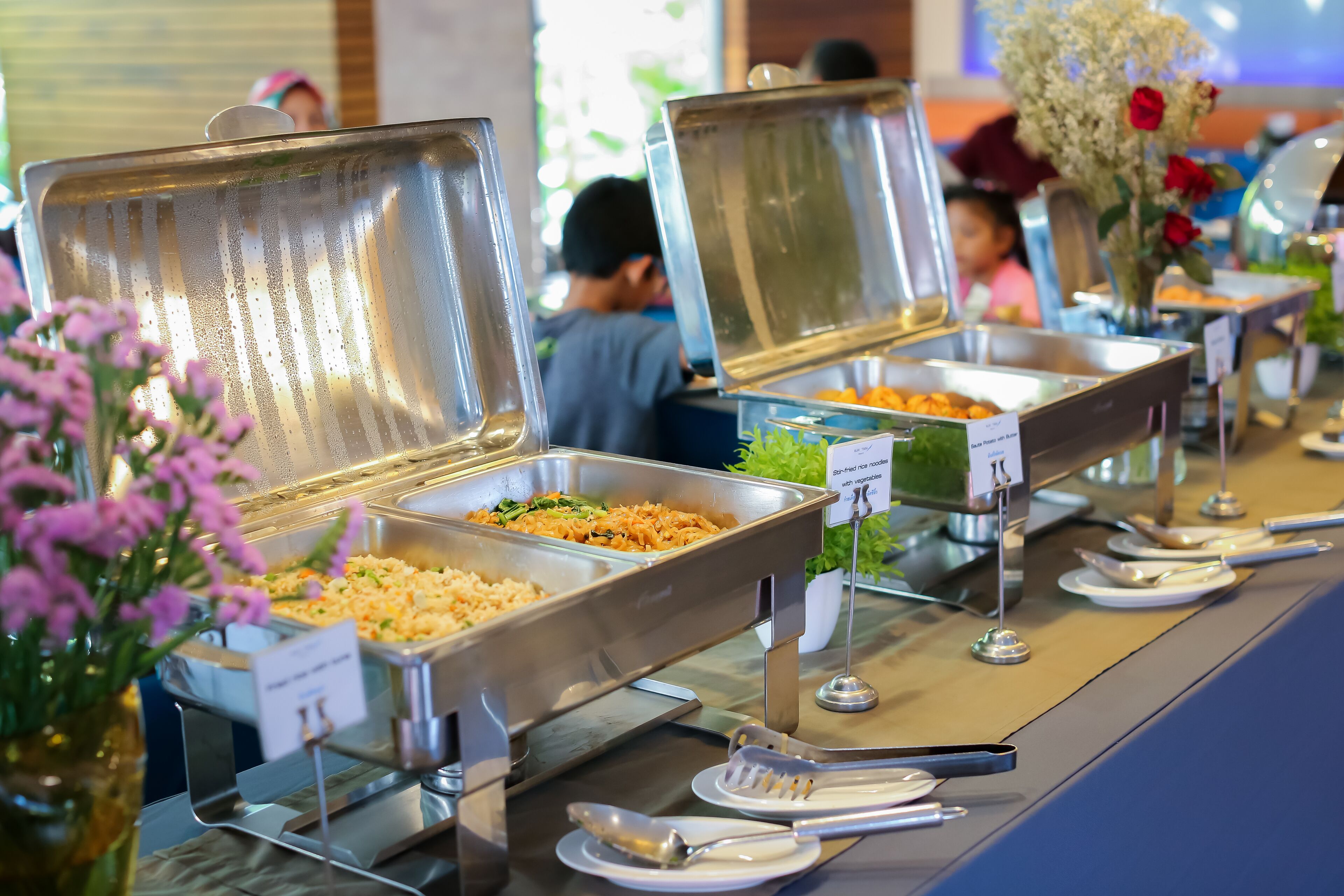 A buffet setup with various food options and serving utensils.
