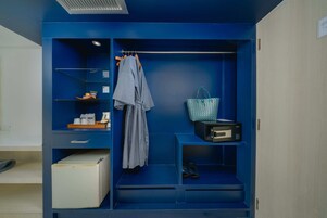 Een blauwe opslagunit met planken, een kledingroede en een koffer.