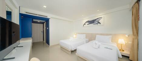 Habitación de hotel con dos camas, un escritorio, un televisor y un cuadro de una ballena en la pared.
