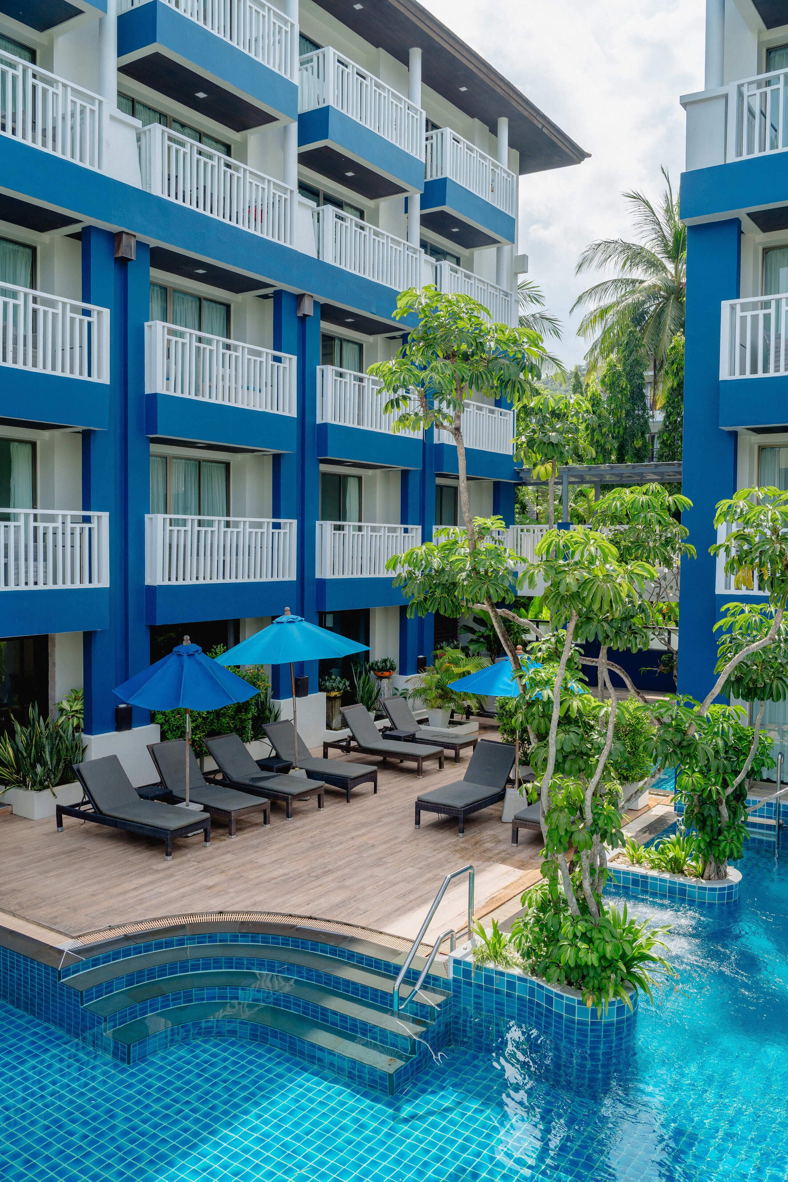 Un hôtel doté d’une piscine, de chaises longues et de parasols.