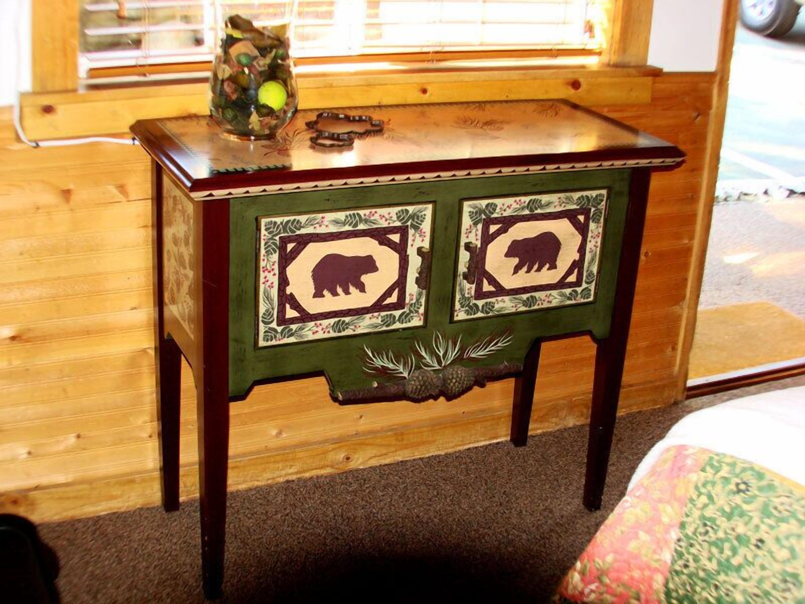 Una mesa de madera con dos recortes con forma de oso, un florero de vidrio con un objeto verde, y una bandeja de madera.