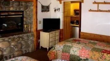 A cozy room with a stone wall, a television, a bed with floral bedding, and a sign that reads "BREOM".