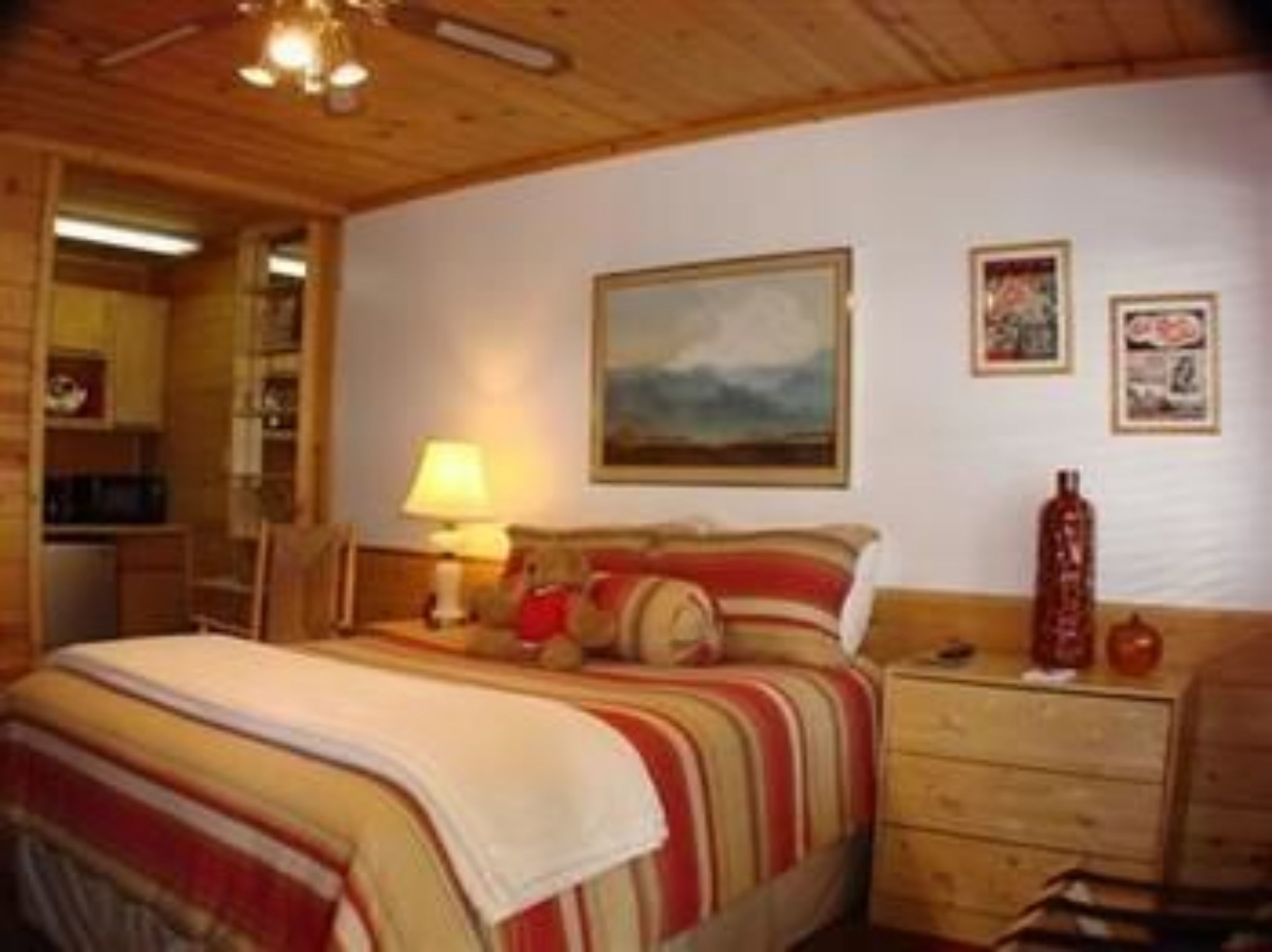 Een gezellig slaapkamer met een bed, een nachtkastje, een lamp en een schilderij aan de muur.