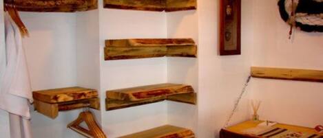 Een kamer met houten planken met diverse spullen, een houten tafel met een stoel, en een hangende decoratie.
