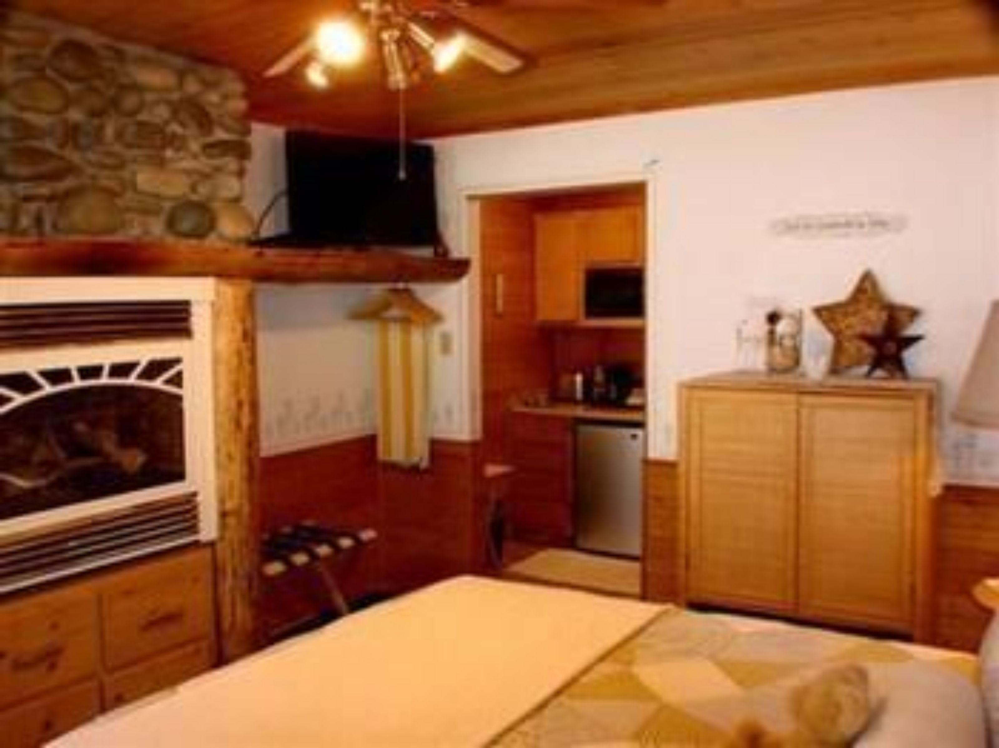 Um quarto aconchegante com lareira, armários de madeira e ventilador de teto.