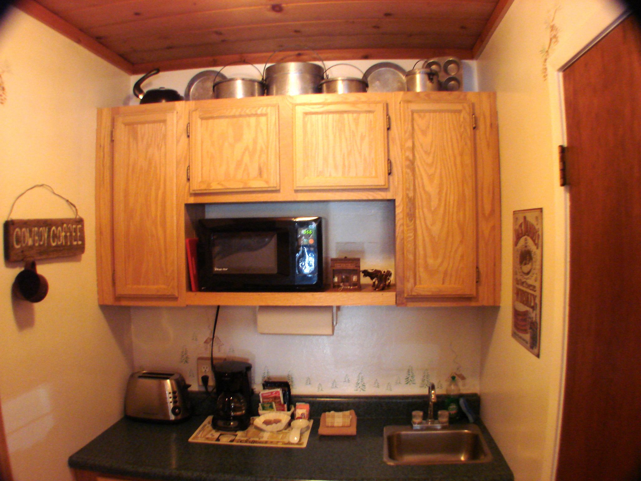 A small kitchen with wooden cabinets, a microwave, a toaster, and a sink.