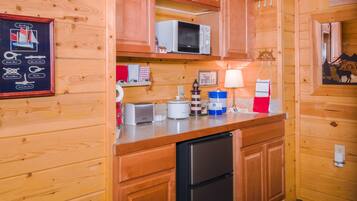A compact kitchen with wooden cabinets, a microwave, a toaster, and a refrigerator.