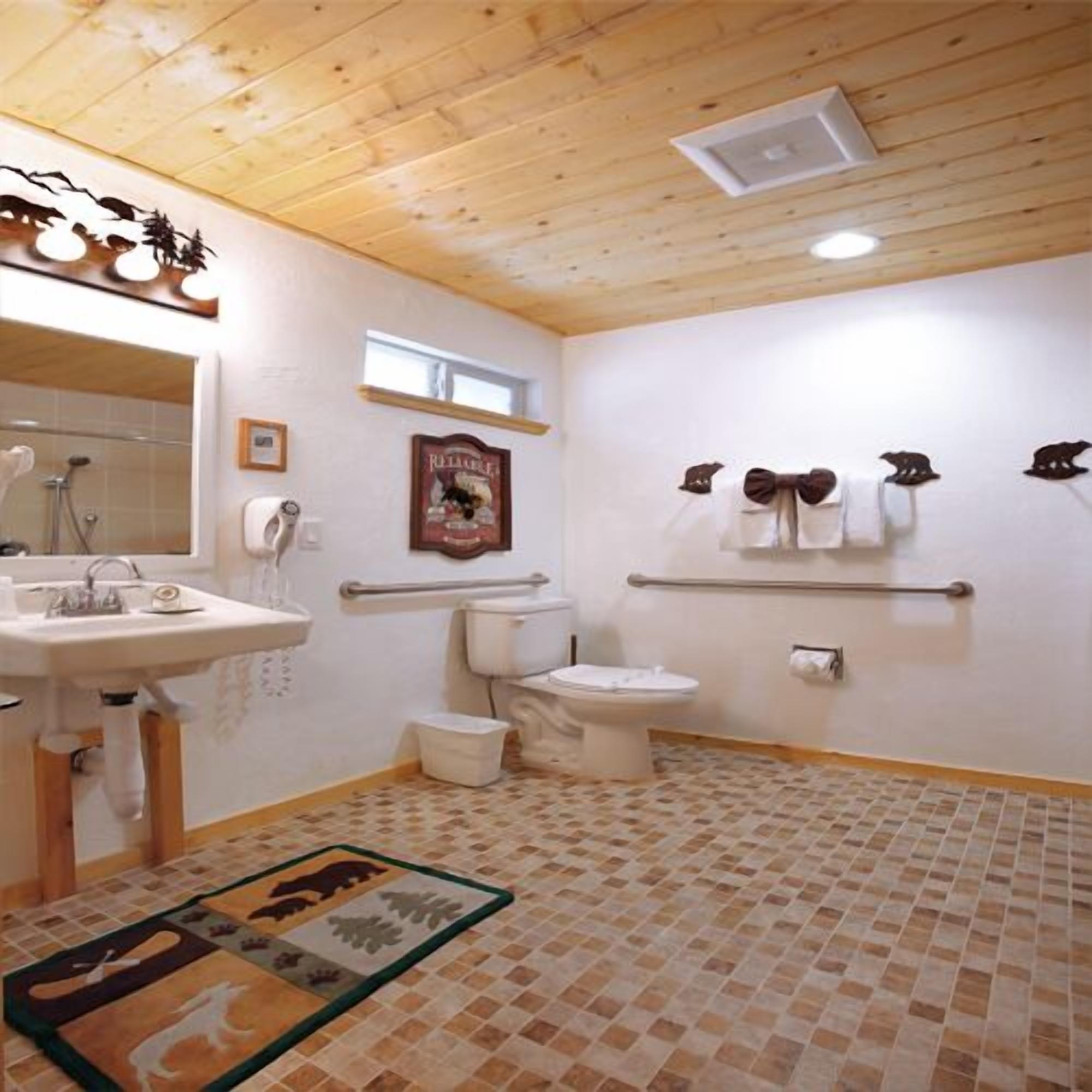 A bathroom with a wooden ceiling, a sink, a toilet, a bidet, and a shower.