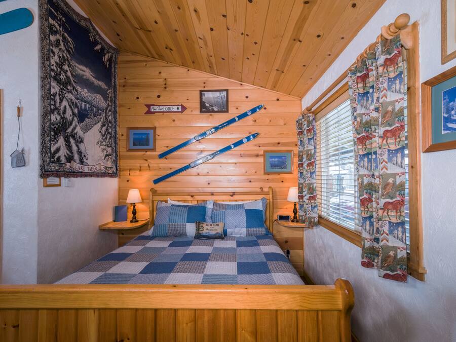 A cozy room with a wooden bed, a checkered quilt, and a mountain-themed tapestry.