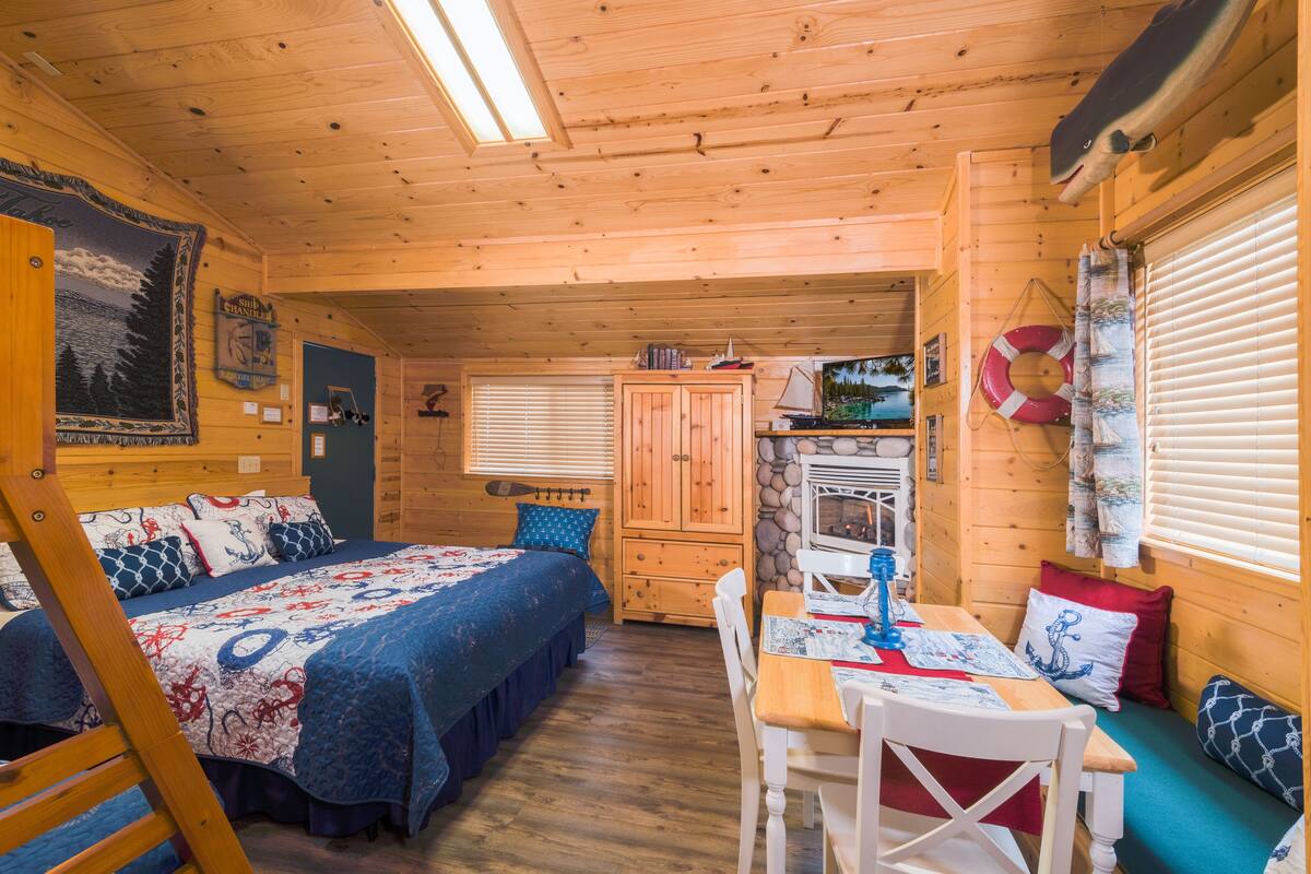A cozy cabin with a bed, a dining area, and a kitchen.