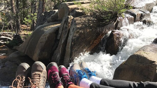 A person sitting by a waterfall with hiking boots and a water bottle. - Fireside Lodge (South Lake Tahoe)