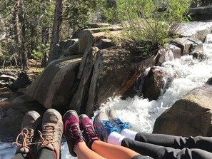 A person sitting by a waterfall with hiking boots and a water bottle. - Fireside Lodge (South Lake Tahoe)
