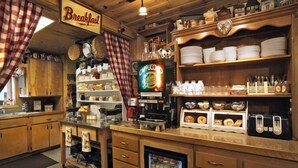 A breakfast area with a coffee machine, shelves with plates and bowls, and a refrigerator with food items. - Fireside Lodge (South Lake Tahoe)