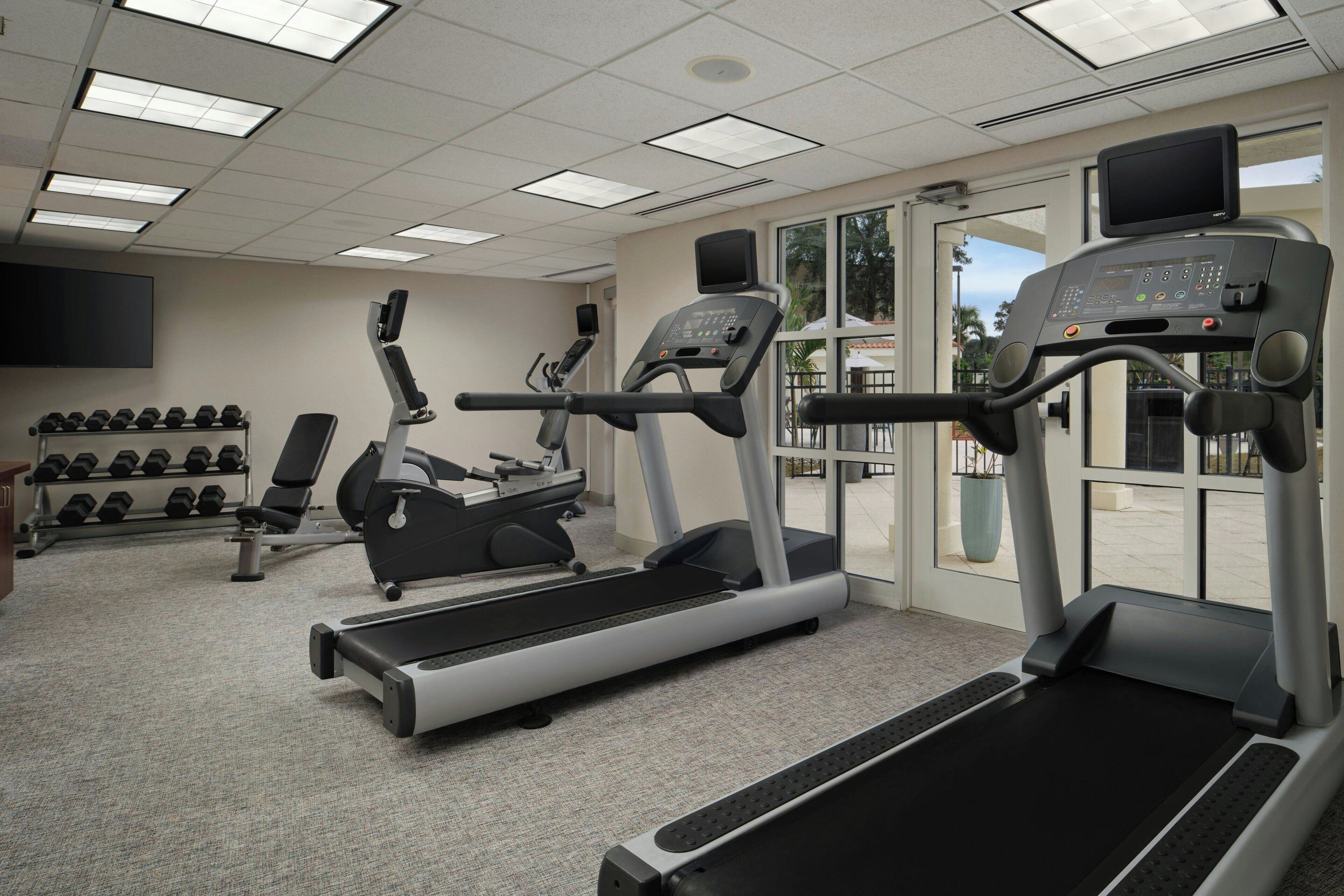 A gym with treadmills, elliptical machines, and dumbbells.