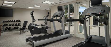 A gym with treadmills, elliptical machines, and dumbbells.
