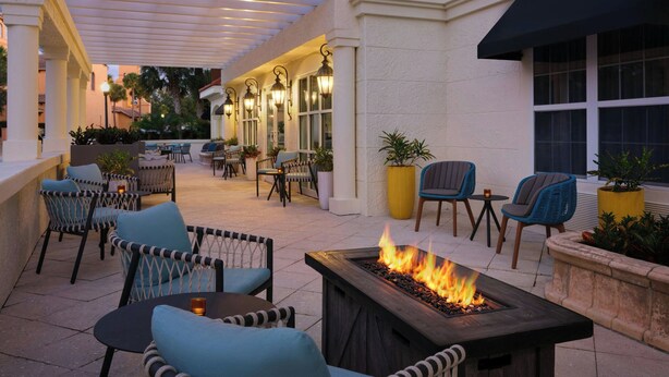 Un patio al aire libre con mobiliario, una chimenea y un paseo cubierto.