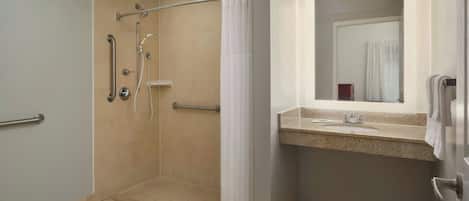 A bathroom with a shower, grab bars, a sink, and a mirror.