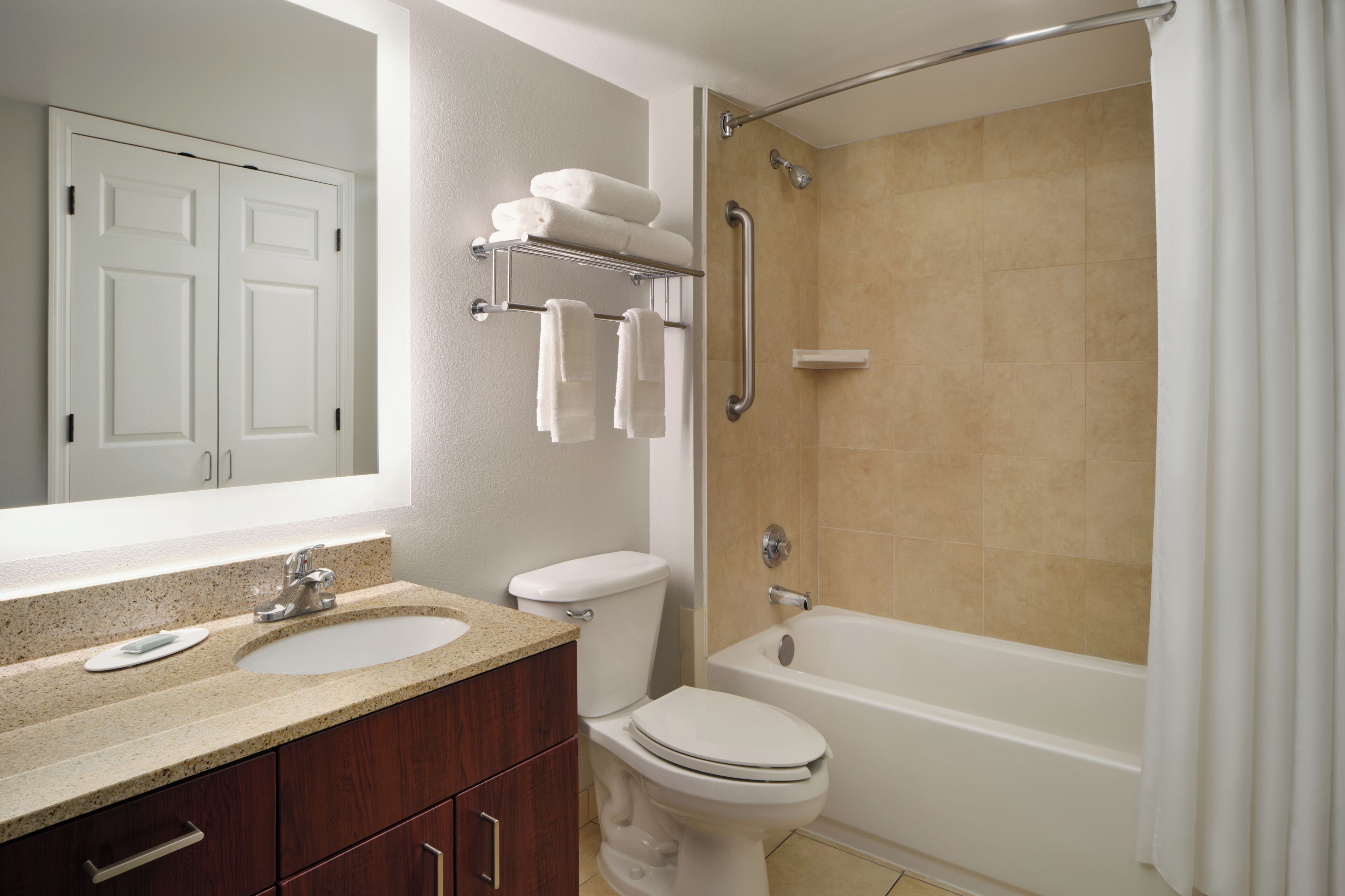 A bathroom with a sink, toilet, bathtub, and a shower with a grab bar.