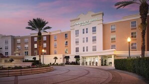 Un hotel con una fuente, palmeras y un letrero que dice 'Towneplace Suites by Marriott'.
