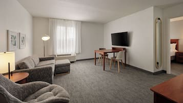 Une chambre d’hôtel avec un canapé, une petite table, une télévision et un miroir.